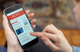 File: A woman reading the news on a phone. GettyImages/izzetugutmen