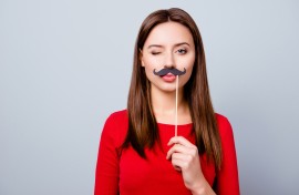 File: A woman holding a paper moustache. GettyImages/Deagreez