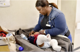 Baby with two casts on their legs being attended by a nurse