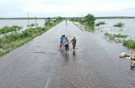 Residents wading through floodwater to cross a road near Maputo. AFP/Emidio Jozine