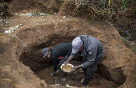 Artisanal miners pan for gold in a hold dug in a patch of land where artisanal miners look for gold outside Springs, Ekurhuleni, on February 15, 2026.