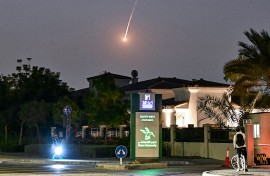 A cyclist watches as a projectile falls over Dubai. AFP