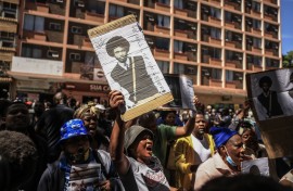 A woman hold a picture of Isaac David Satlat outside the Pretoria Magistrate's Court. Gallo Images/Phill Magakoe