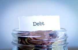 A  close-up shot of the word Debt on a jar of coins. GettyImages/Synergee