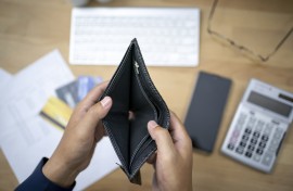 File: A person looking at an empty wallet with a calculator and credit cards. GettyImages/seksan Mongkhonkhamsao
