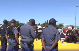 Police officers keeping an eye on demonstrators outside the Buthelezi Mall.