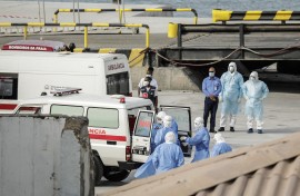 Health personnel returning from the cruise ship MV Hondius, are seen at the port of Praia, the capital of Cape Verde, as individuals wearing hazmat suits are helped into an ambulance on May 6, 2026.