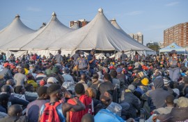 Police officers keep order as hundreds of newly displaced foreign nationals take refuge at the old Durban Drive Inn in Durban. AFP/Rajesh Jantilal