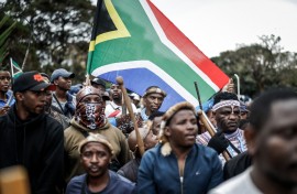 Members of the Zulu regiment known as the ‘Amabutho’ hold a South African flag as they march during a demonstration by the "March and March" movement. AFP/Marco Longari