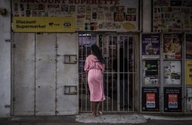 File: A resident wearing a bathrobe buys last minutes goods from a half closed shop. AFP/Marco Longari