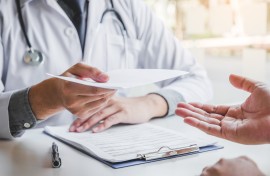  Doctor or physician writing diagnosis and giving a medical prescription to male Patient. Getty Images SARINYAPINNGAM