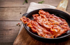 Hot fried crispy bacon slices in a skillet. GettyImages/LumenSt