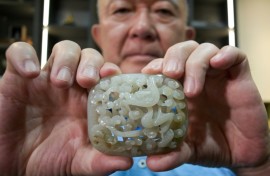 Chang Juben, chairman of Taiwan's Association of Jade Collectors, shows a Yuan dynasty jade belt ornament featuring a carving of a dragon among clouds