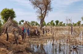 Children stand among the rooftops of homes destroyed by floodwaters in Yusuf Batir refugee camp in Maban, South Sudan, on November 25, 2019 -- UNICEF says tens of millions of children were displaced by climate disasters from 2016 to 2021