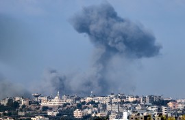 This aerial view shows people standing before destroyed buildings at the site of the Ahli Arab hospital in central Gaza on October 18, 2023 in the aftermath of an overnight strike there. 