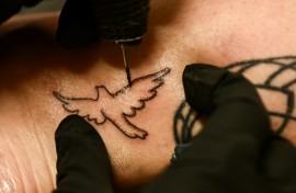 Tattoo artist Kat Dukes inks a hand poked tattoo of a dove on Scout Frank using ink mixed with the ashes of Frank’s cremated mother in Oceanside, California on October 6, 2023