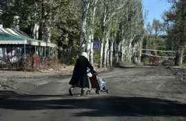 An elderly woman carries bottles of water in a child stroller down a street in the frontline town of Chasiv Yar in eastern Ukraine