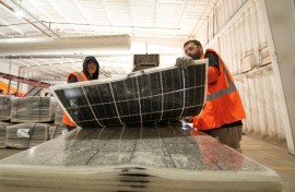 Workers push damaged solar panels into a machine to be recycled at the We Recycle Solar plant in Yuma, Arizona 