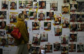 A woman looks at portraits of Israeli hostages on the sidelines of a rally calling for their release, in Tel Aviv