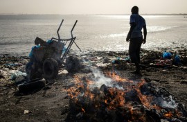 A man dumps waste into the ocean at Hann Bay
