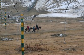 A guide leads horses along a path near ski slopes usually covered in snow in Gulmarg 