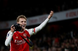 Martin Odegaard picks up a camera and takes pictures after Arsenal's win over Liverpool
