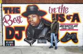 Local resident Jacob Rosthein poses before a mural paying tribute to late Run-DMC's Jam Master Jay in the Hollis neighborhood of Queens, as the trial into artist's murder gets underway