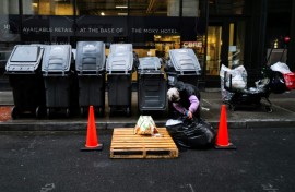 A woman searches through a trash bag in Manhattan on March 20, 2024