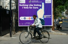 A man rides past an election awareness poster displayed on a street ahead of India’s upcoming general elections, in Hyderabad 