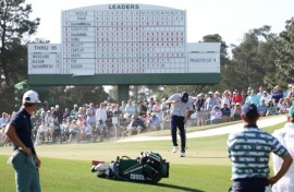 Bryson DeChambeau of the United States shields himself from the wind, blowing sand, on the 17th green at the Masters on Friday.