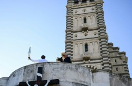 Basile Boli holds the Olympic torch aloft in front of the basilica of Notre-Dame de la Garde in Marseille