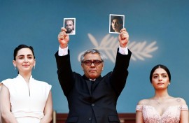 Mohammad Rasoulof of Iran held pictures of his actors on the red carpet