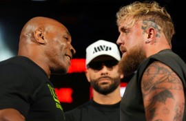 Mike Tyson, left, and Jake Paul, right, stare at each other while promoter Nakisa Bidarian, center, looks on ahead of their heavyweight boxing showdown, which has been rescheduled for November 15
