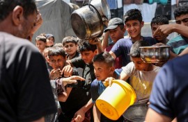 Children queue in Jabalia refugee camp to receive food aid from a kitchen at the Abu Zeitun school run by UNRWA, the UN agency for Palestinian refugees