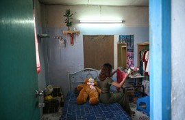 "Khaing", a former teacher, beside a large teddy bear gifted to her by a friend who knew she was feeling lonely