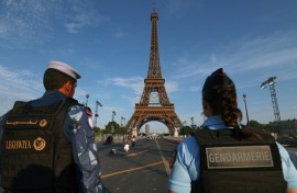 A French policewoman and a Qatari policeman stand guard near the Eiffel Tower as security preparations step up for the Paris Olympics