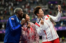 Winners of the women's hammer throw take a selfie with a Samsung flip phone 
