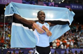 Letsile Tebogo poses with the Botswana flag after a stunning run to win 200m gold at the Paris Olympics 