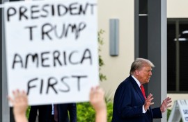 A supporter holds up a sign as former US President and Republican presidential candidate Donald Trump leaves after casting his vote in Florida's primary election on August 14, 2024 in West Palm Beach, Florida