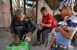 Palestinians wait for a cobbler to repair their shoes in Khan Yunis in the southern Gaza Strip