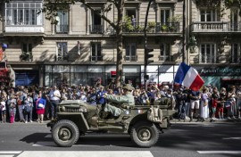 Reenactors dressed in wartime uniforms parade on wartime military vehicles during a reenactment marking the 80th anniversary of the liberation of Paris from the Germans during World War II