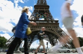 Pedestrians walk past the Eiffel Tower adorned with the Olympic Rings ahead of the 2024 Olympic Games in Paris in July 16, 2024.