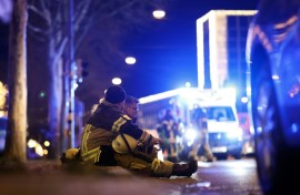 Two rescuers sit on the ground to rest after a car crashed into a crowd at a Christmas market injuring more than 60 people in Magdeburg, eastern Germany  
