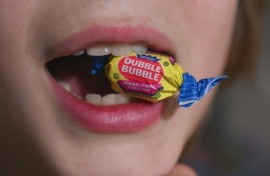 A boy holds a wrapped Dubble Bubble Bubble Gum candy in his mouth, a product that uses Red Dye No 3, in this illustration photograph on December 27, 2024