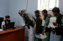 Afghan men stand in queue to submit their documents as they apply for passport in Herat