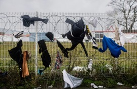 Drenched clothes hang on a barbed wire fence nearby
