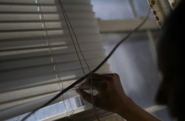 Rosario peers through her window blinds for any lurking US ICE agents outside her building