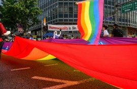 Participants in South Korea's annual Pride parade in Seoul carry a huge flag in support of LGBTQ rights past opponents holding a banner that reads "Homosexuality is sin!"