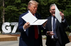 US President Donald Trump holds a signed US-UK trade deal next to British Prime Minister Keir Starmer