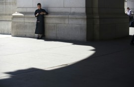A chef takes a break to check his phone in a sliver of shade outside Union Station on August 12, 2016 in Washington,DC